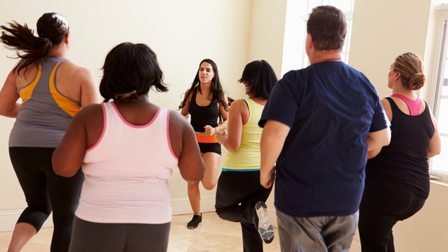 A group of ethnically diverse adults take part in an indoor exercise class